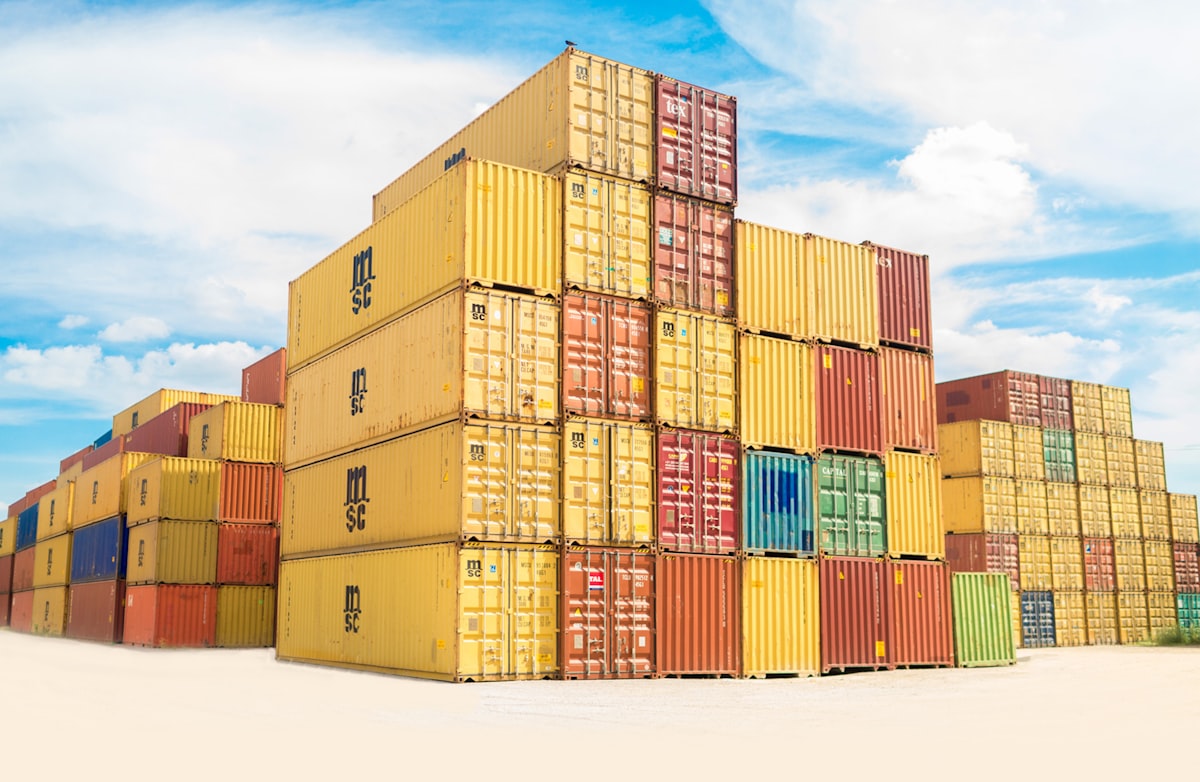 Stacked shipping containers at port under bright blue sky